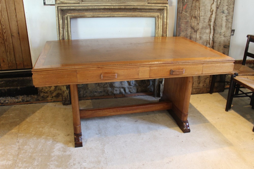 An Art Deco walnut desk featuring a rectangular top with an inset writing surface, frieze drawers with ribbed handles, and a trestle-style base with a low stretcher. View II