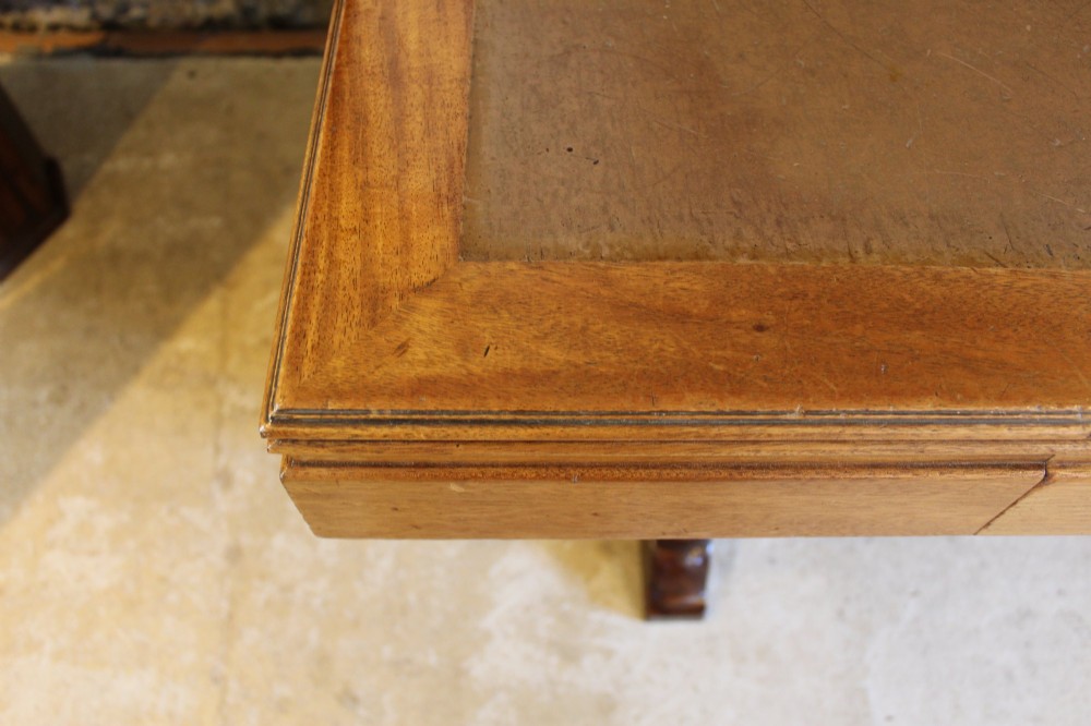 An Art Deco walnut desk featuring a rectangular top with an inset writing surface, frieze drawers with ribbed handles, and a trestle-style base with a low stretcher. View VI
