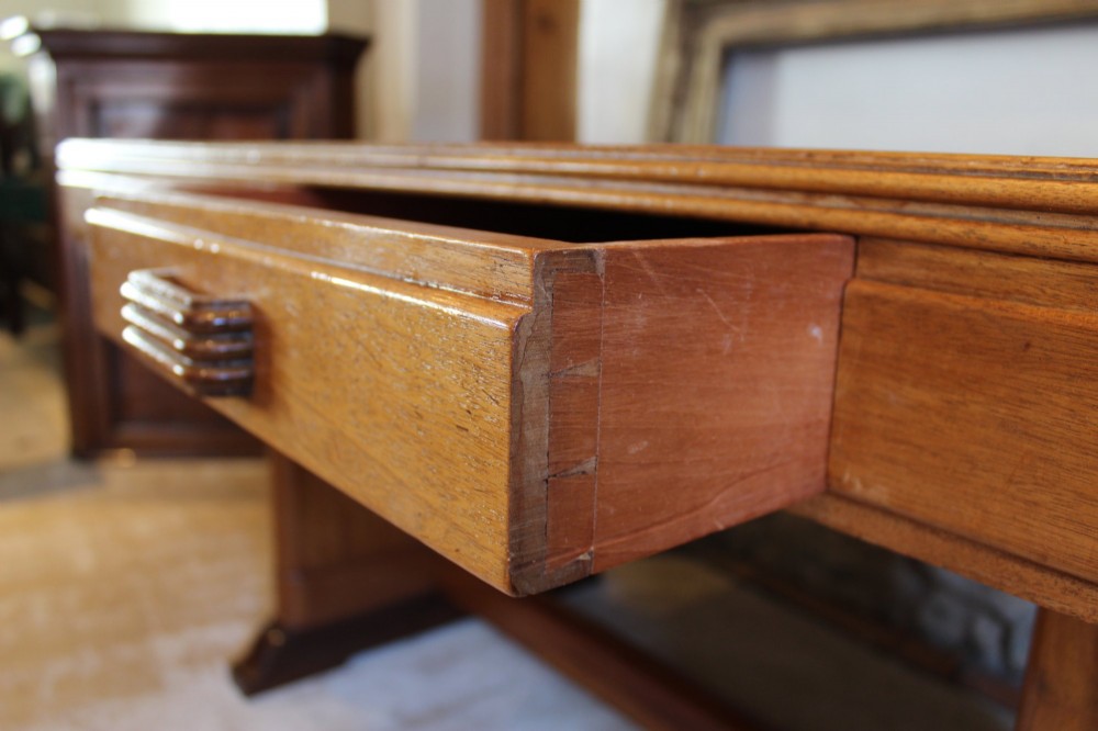 An Art Deco walnut desk featuring a rectangular top with an inset writing surface, frieze drawers with ribbed handles, and a trestle-style base with a low stretcher. View VIII
