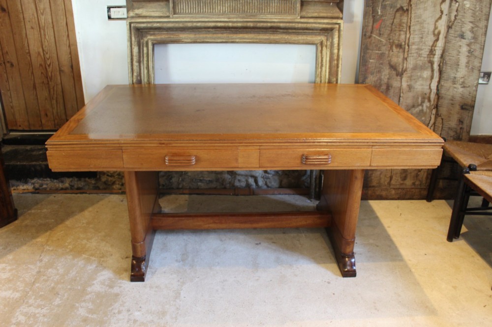 An Art Deco walnut desk featuring a rectangular top with an inset writing surface, frieze drawers with ribbed handles, and a trestle-style base with a low stretcher. View IX