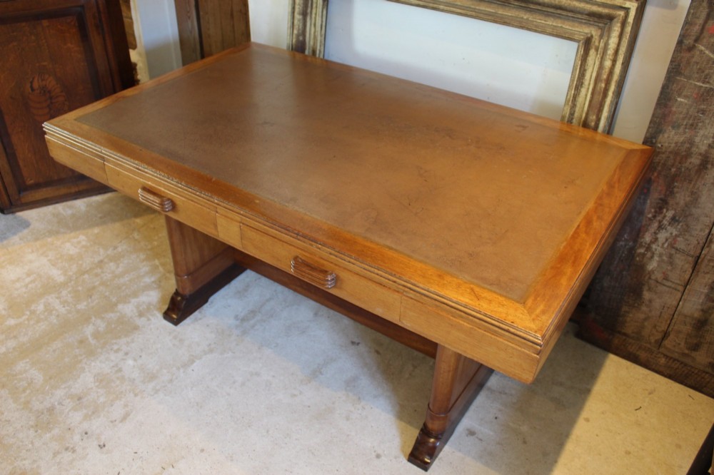 An Art Deco walnut desk featuring a rectangular top with an inset writing surface, frieze drawers with ribbed handles, and a trestle-style base with a low stretcher. View XI