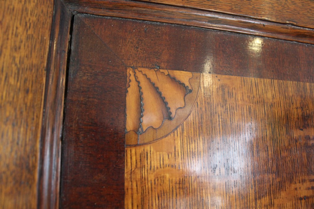 An 18th-century Georgian oak corner cupboard featuring a central inlaid shell motif on the single panel door and decorative crossbanding. View VI