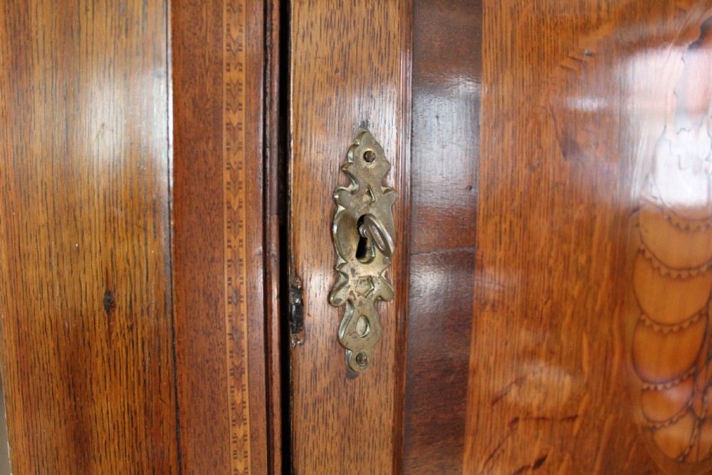 An 18th-century Georgian oak corner cupboard featuring a central inlaid shell motif on the single panel door and decorative crossbanding. View X
