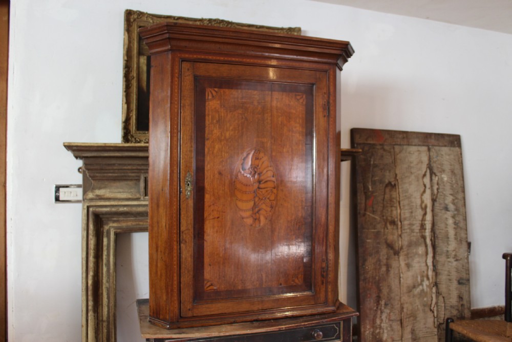 An 18th-century Georgian oak corner cupboard featuring a central inlaid shell motif on the single panel door and decorative crossbanding. View XII