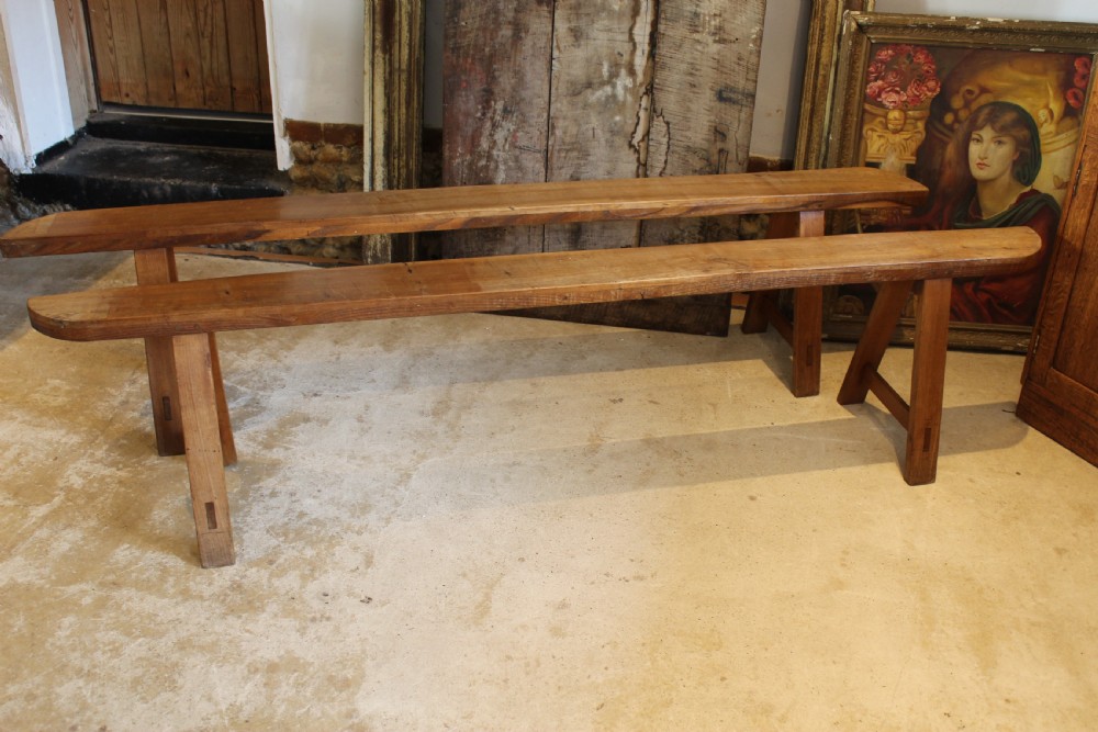 A pair of long 19th-century French fruitwood refectory benches featuring A-frame trestle legs and pegged joinery. View II