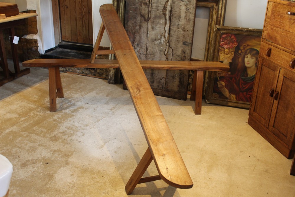 A pair of long 19th-century French fruitwood refectory benches featuring A-frame trestle legs and pegged joinery. View V