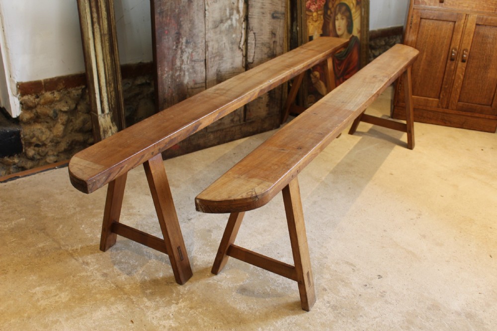 A pair of long 19th-century French fruitwood refectory benches featuring A-frame trestle legs and pegged joinery. View X