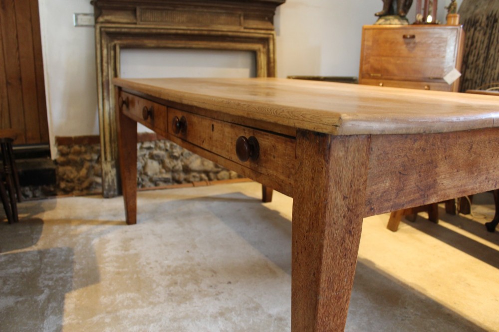 A late Victorian oak farmhouse dining table featuring a plain rectangular top, frieze drawers with wooden turned knobs, and square tapered legs. View VIII
