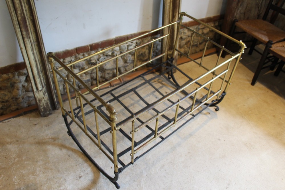 A Victorian brass and black wrought iron rocking cot featuring tubular side rails, finial accents, and a curved iron base. View II