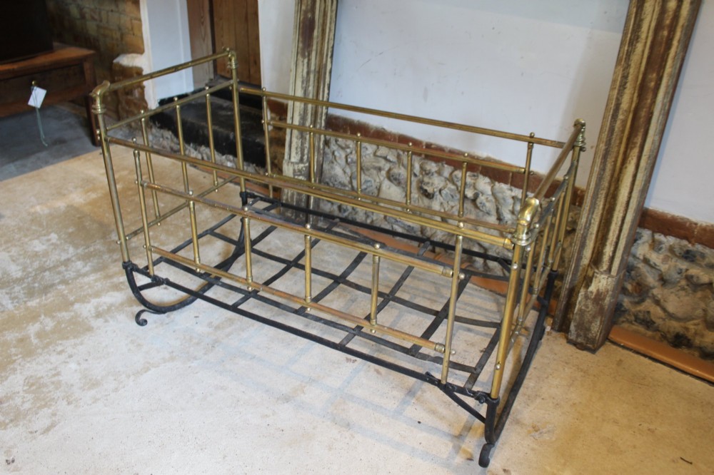 A Victorian brass and black wrought iron rocking cot featuring tubular side rails, finial accents, and a curved iron base. View VII