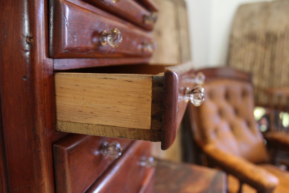 A Victorian miniature wooden chest of five graduated drawers with small metal knobs and a solid base. View VI