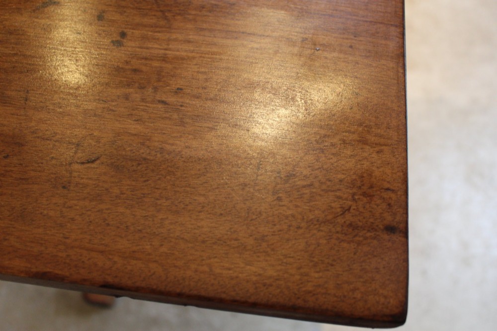 A solid teak Arts and Crafts refectory table featuring twin upright trestle supports resting on shoe feet and joined by a low stretcher rail. View III