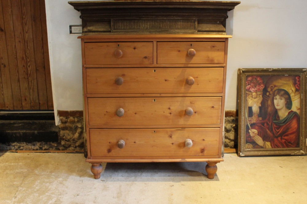 A Victorian pine chest of drawers featuring two short drawers over three long drawers with turned wooden handles and turned bun feet. View II
