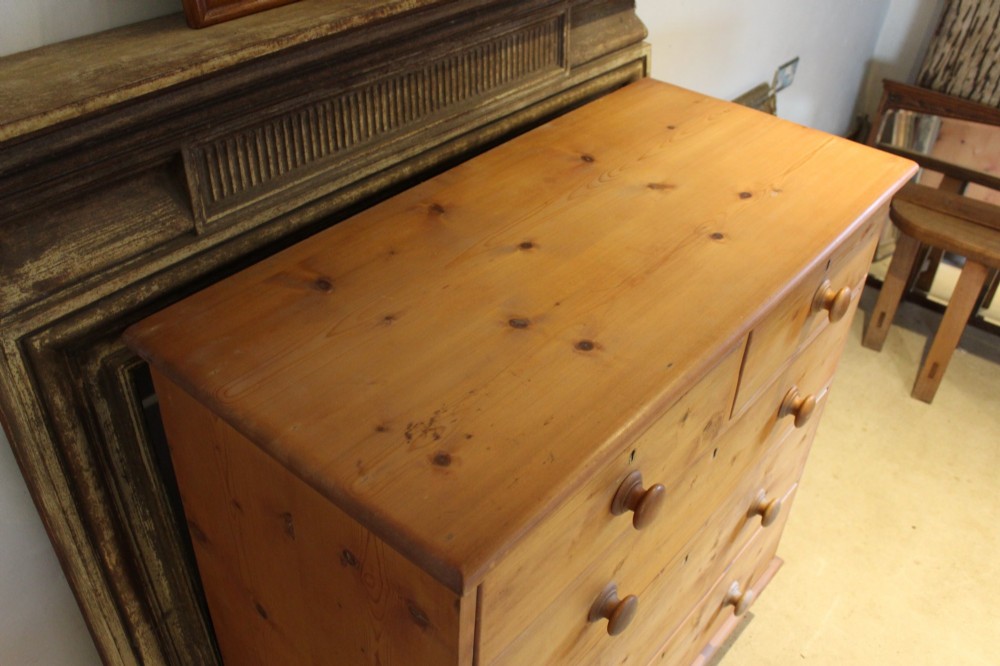 A Victorian pine chest of drawers featuring two short drawers over three long drawers with turned wooden handles and turned bun feet. View V
