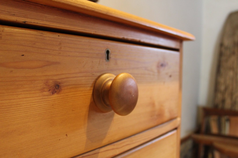 A Victorian pine chest of drawers featuring two short drawers over three long drawers with turned wooden handles and turned bun feet. View VI