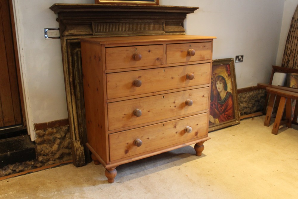 A Victorian pine chest of drawers featuring two short drawers over three long drawers with turned wooden handles and turned bun feet. View VIII