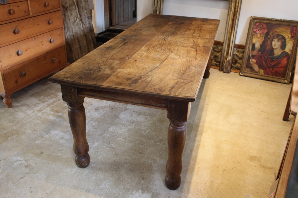 A large Edwardian oak refectory dining table with a rectangular plank top and sturdy turned legs.