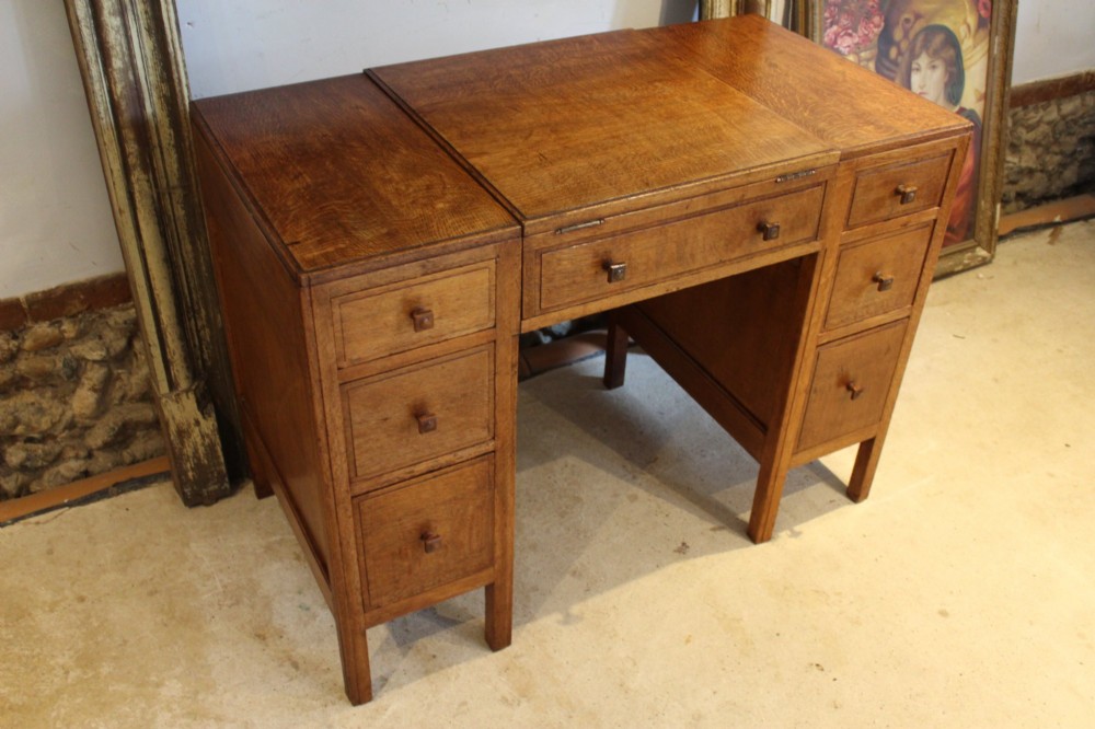 An antique golden oak dressing table featuring a central flip-top section, side drawer pedestals, and square wooden handles. View XI
