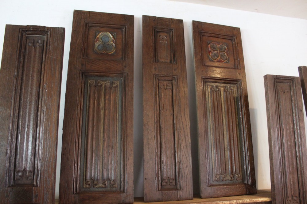 A collection of 16th and 17th-century carved oak panels displaying intricate linenfold and Gothic tracery relief motifs in dark brown tones. View II