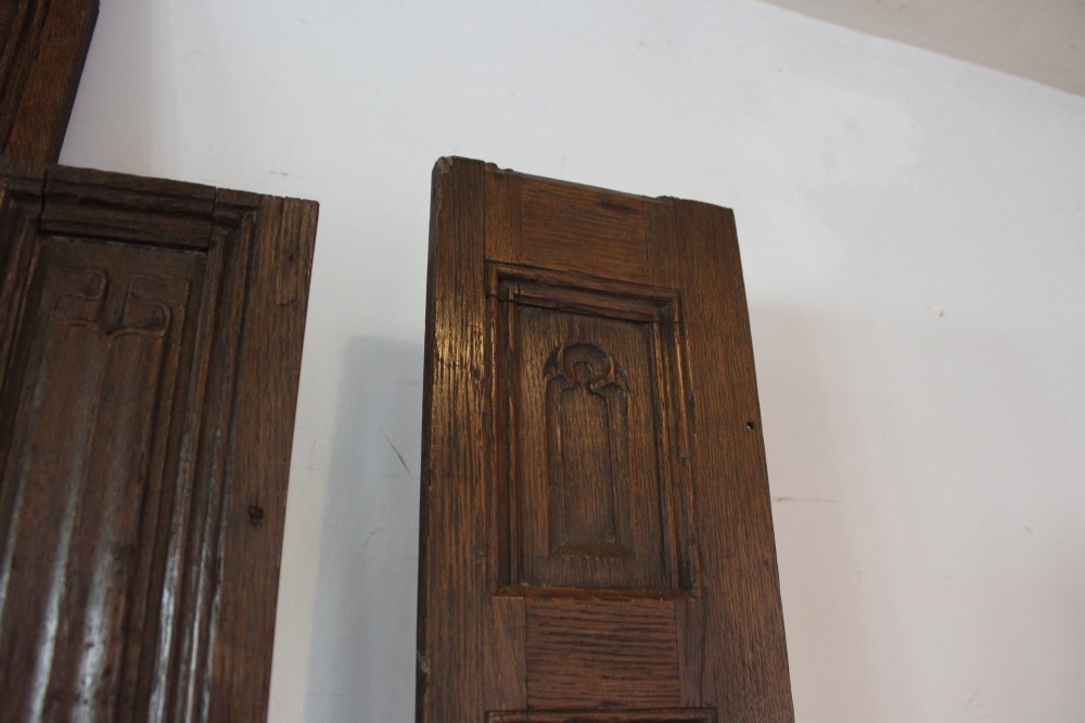 A collection of 16th and 17th-century carved oak panels displaying intricate linenfold and Gothic tracery relief motifs in dark brown tones. View X
