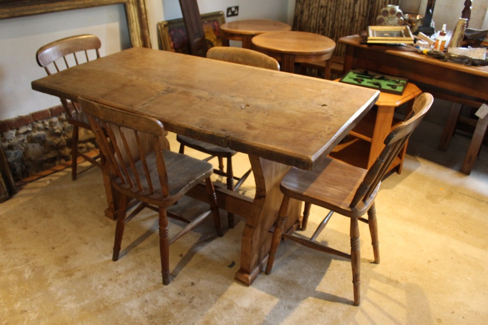 A solid oak refectory dining table featuring a rectangular plank top and a trestle base with a central stretcher held by a wedge. View IV