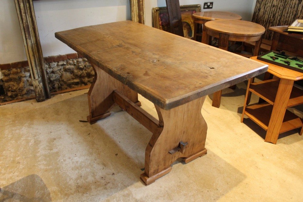 A solid oak refectory dining table featuring a rectangular plank top and a trestle base with a central stretcher held by a wedge. View VI