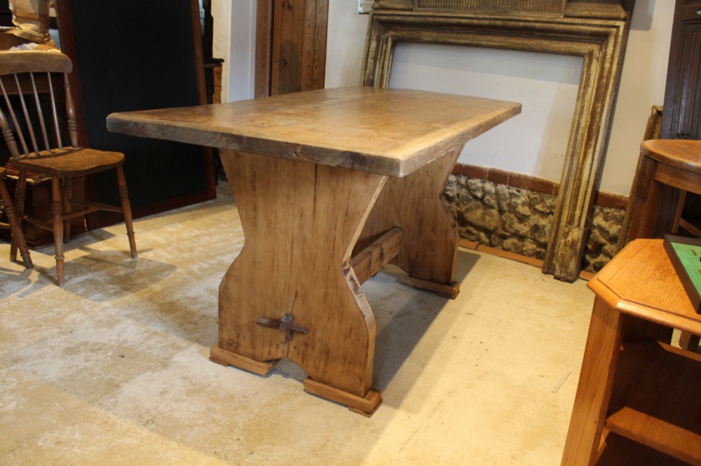A solid oak refectory dining table featuring a rectangular plank top and a trestle base with a central stretcher held by a wedge. View IX