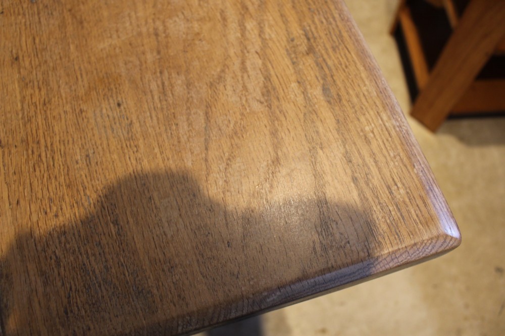 An antique solid oak refectory dining table featuring a thick rectangular top supported by shaped trestle end supports connected by a low stretcher with keyed tenons. View II