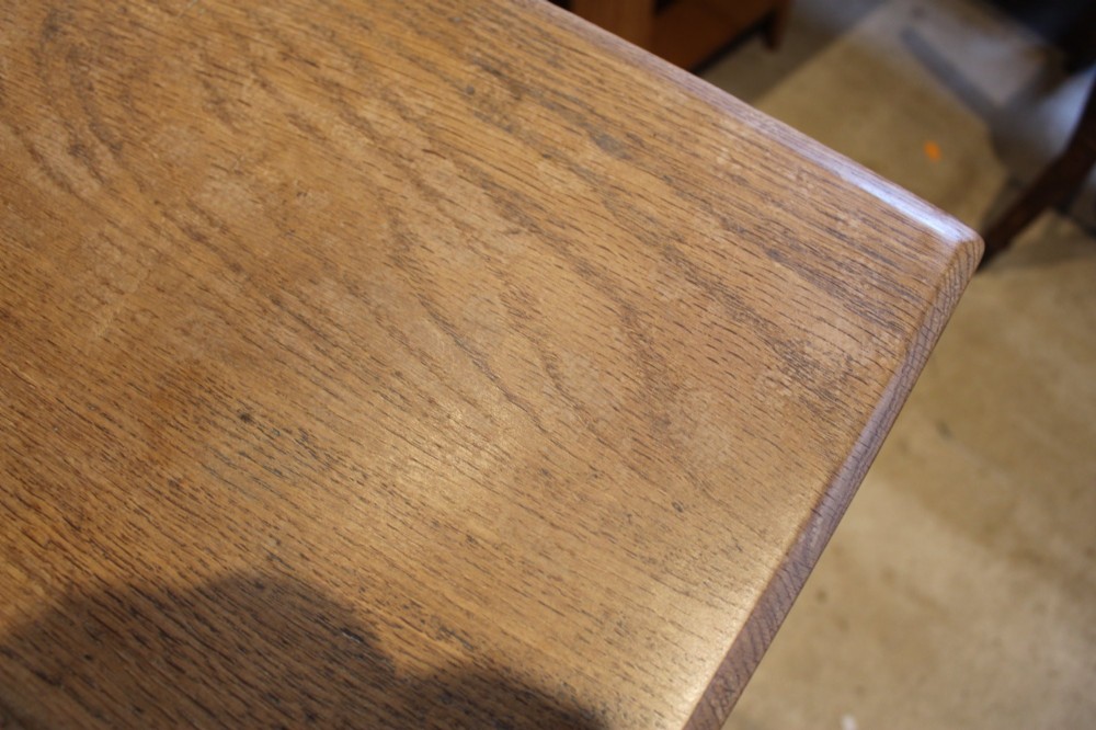 An antique solid oak refectory dining table featuring a thick rectangular top supported by shaped trestle end supports connected by a low stretcher with keyed tenons. View VI