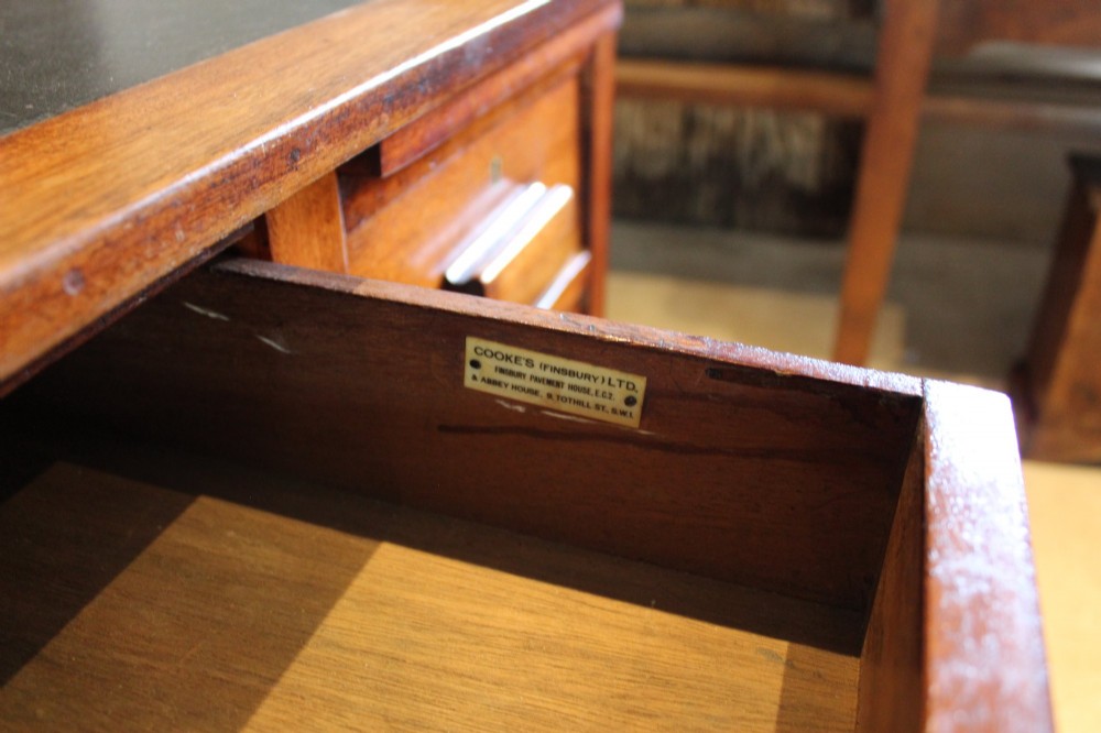 An Art Deco walnut pedestal desk featuring a black leather inset top, a central drawer, and six side drawers with wooden bar handles. View III