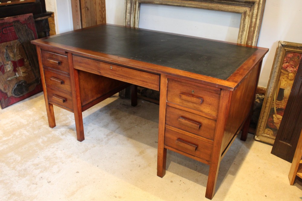 An Art Deco walnut pedestal desk featuring a black leather inset top, a central drawer, and six side drawers with wooden bar handles. View IV
