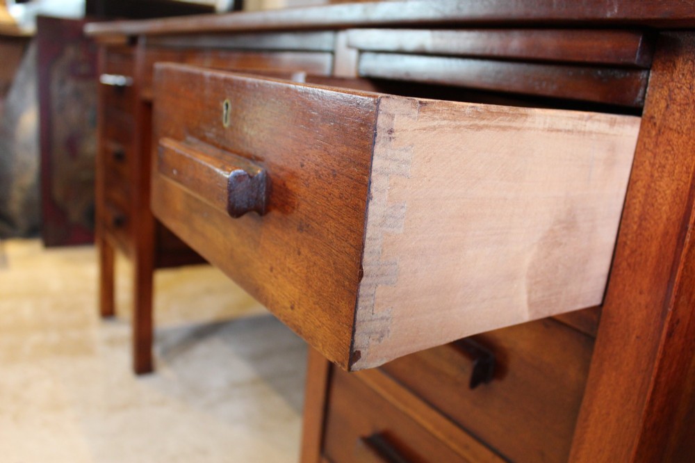 An Art Deco walnut pedestal desk featuring a black leather inset top, a central drawer, and six side drawers with wooden bar handles. View VI