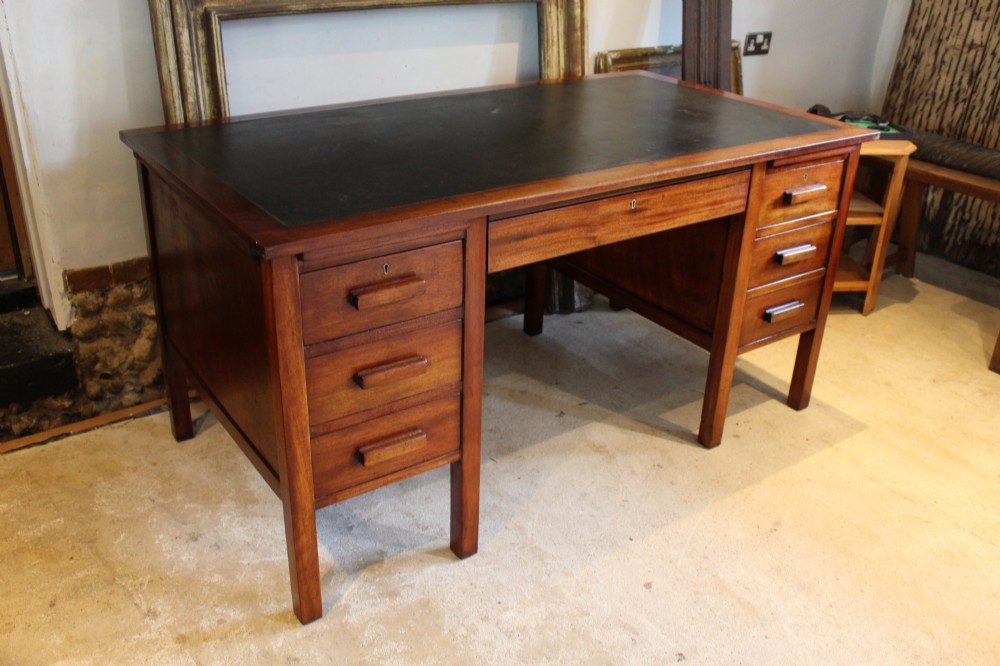 An Art Deco walnut pedestal desk featuring a black leather inset top, a central drawer, and six side drawers with wooden bar handles. View VII