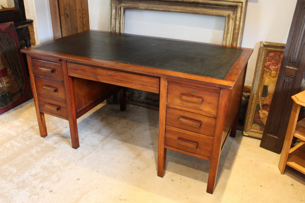 An Art Deco walnut pedestal desk featuring a black leather inset top, a central drawer, and six side drawers with wooden bar handles. View IX
