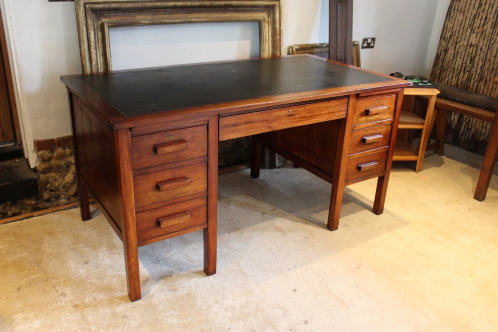 An Art Deco walnut pedestal desk featuring a black leather inset top, a central drawer, and six side drawers with wooden bar handles. View X