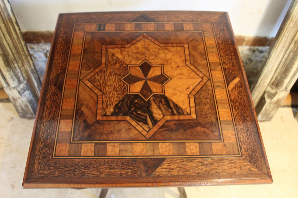 A square Victorian side table featuring geometric star-patterned specimen wood marquetry, curved legs, and a matching central undertier. View II