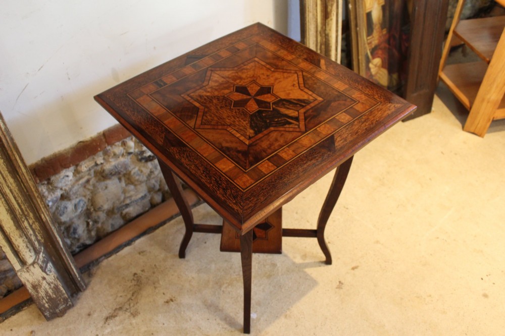 A square Victorian side table featuring geometric star-patterned specimen wood marquetry, curved legs, and a matching central undertier. View V