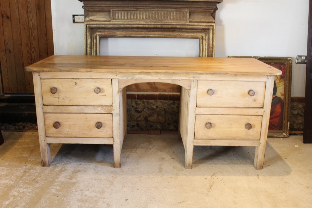 A George III scrubbed pine kneehole desk featuring four side drawers with turned wood handles and an arched central opening. View II