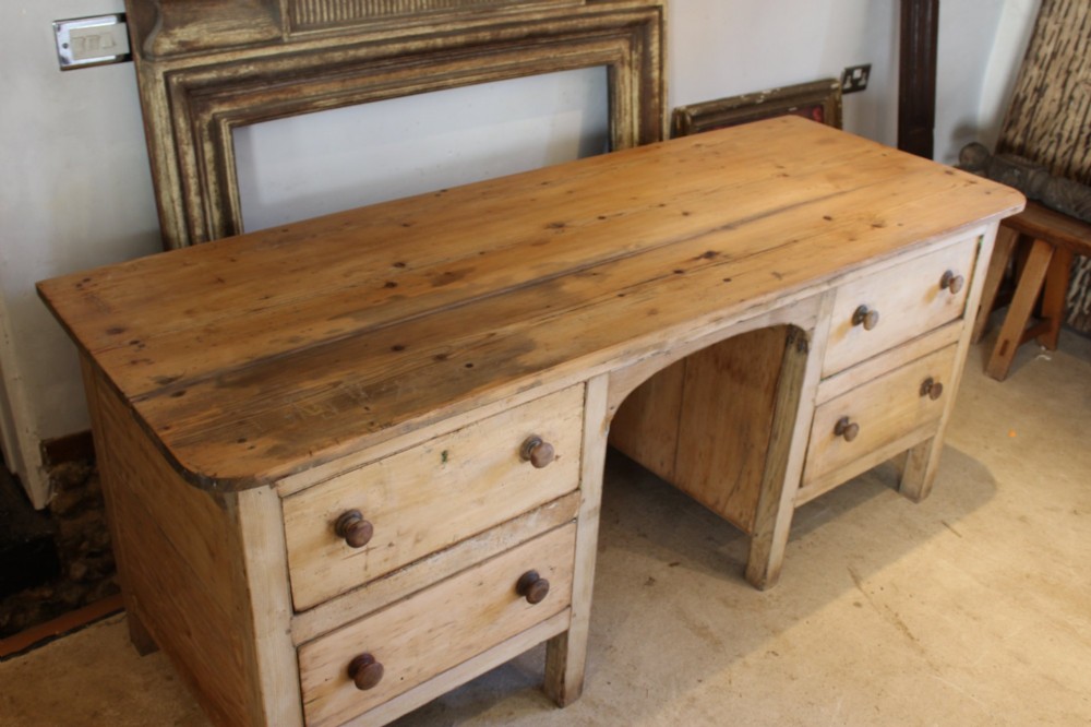 A George III scrubbed pine kneehole desk featuring four side drawers with turned wood handles and an arched central opening. View III