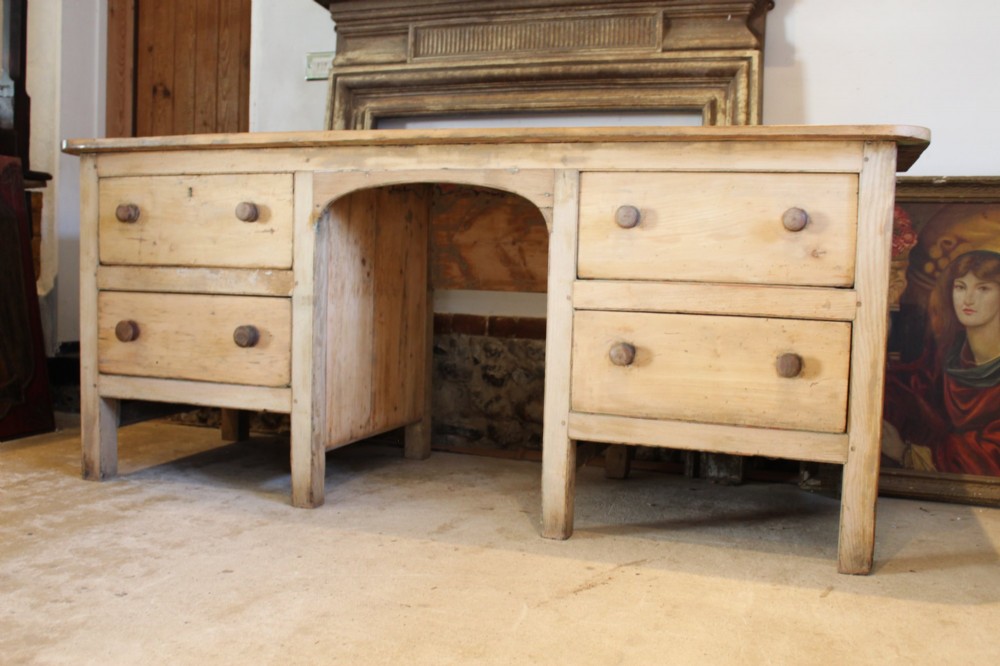 A George III scrubbed pine kneehole desk featuring four side drawers with turned wood handles and an arched central opening. View VI