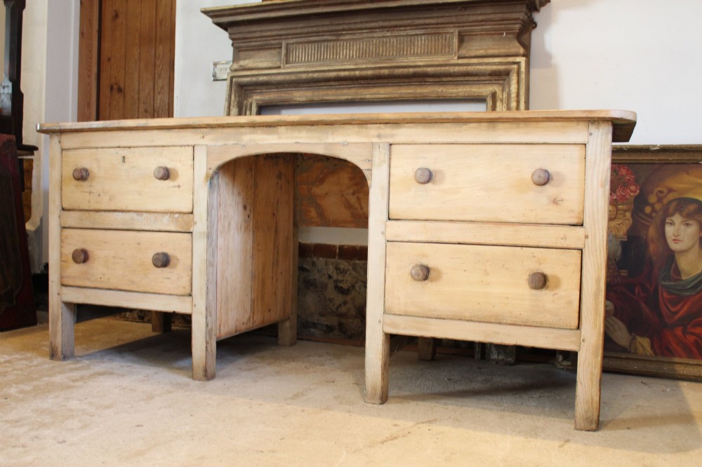 A George III scrubbed pine kneehole desk featuring four side drawers with turned wood handles and an arched central opening. View X
