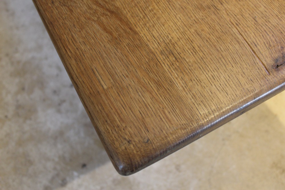 An Arts and Crafts solid oak refectory dining table featuring curved trestle legs and a pegged stretcher. View VII