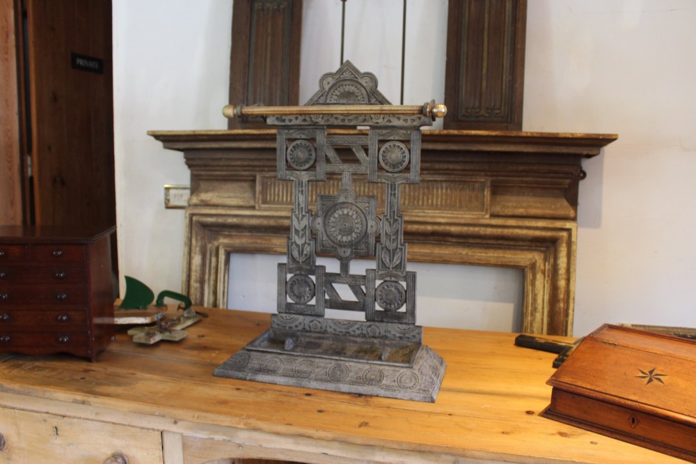A Victorian cast iron stick stand featuring intricate geometric lattice patterns, a central floral rosette medallion, and a brass top rail over a rectangular drip tray.