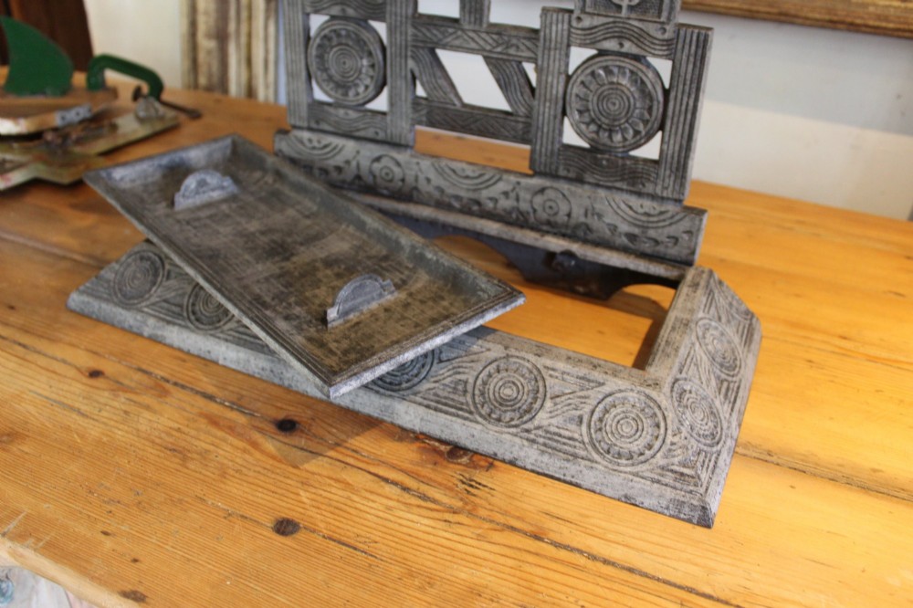 A Victorian cast iron stick stand featuring intricate geometric lattice patterns, a central floral rosette medallion, and a brass top rail over a rectangular drip tray. View VI