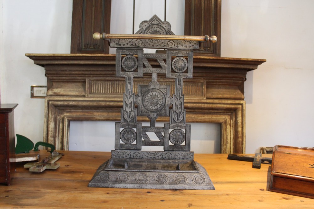 A Victorian cast iron stick stand featuring intricate geometric lattice patterns, a central floral rosette medallion, and a brass top rail over a rectangular drip tray. View X