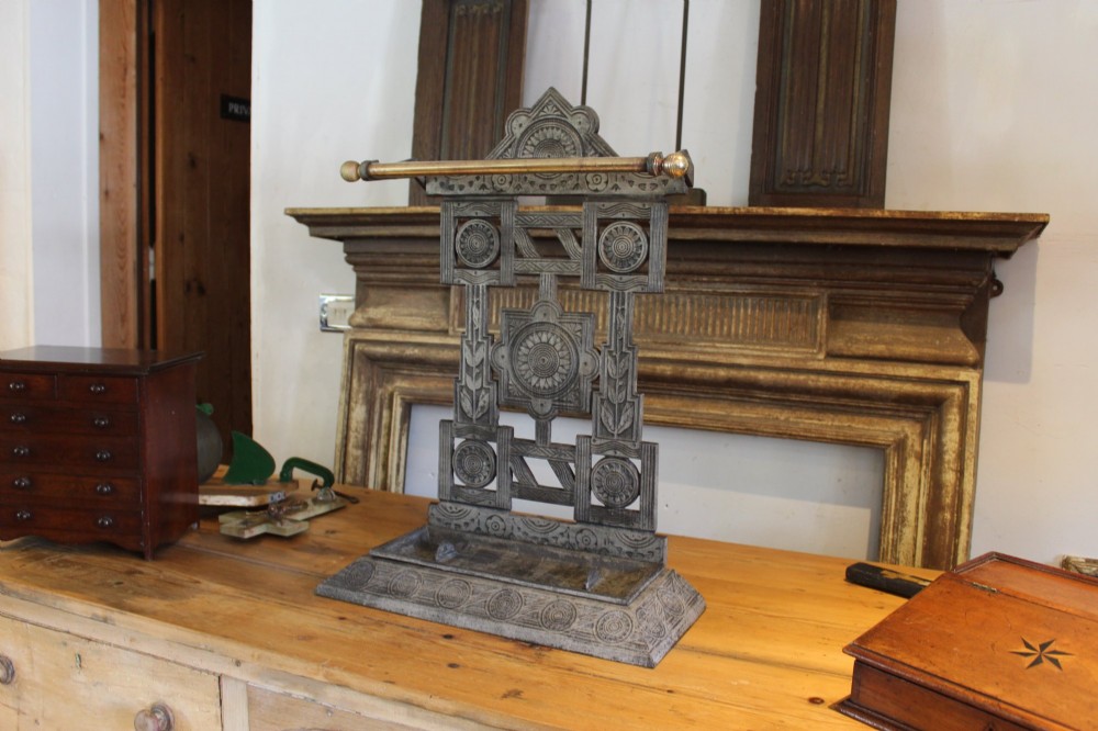 A Victorian cast iron stick stand featuring intricate geometric lattice patterns, a central floral rosette medallion, and a brass top rail over a rectangular drip tray. View XI