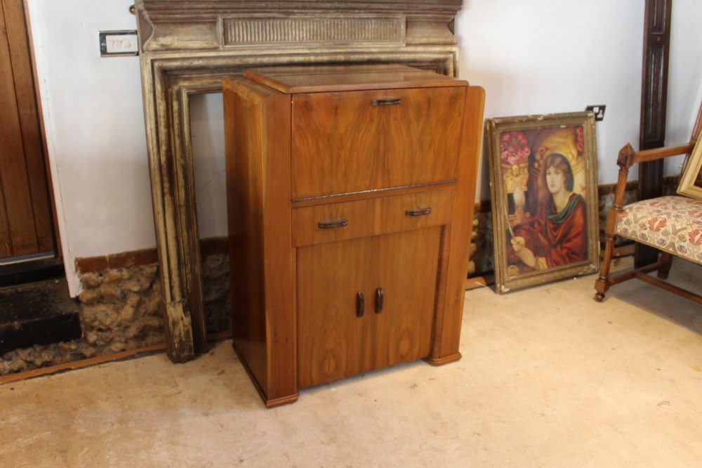 An Art Deco walnut bureau featuring a fall-front writing compartment above a single drawer and a two-door cupboard.
