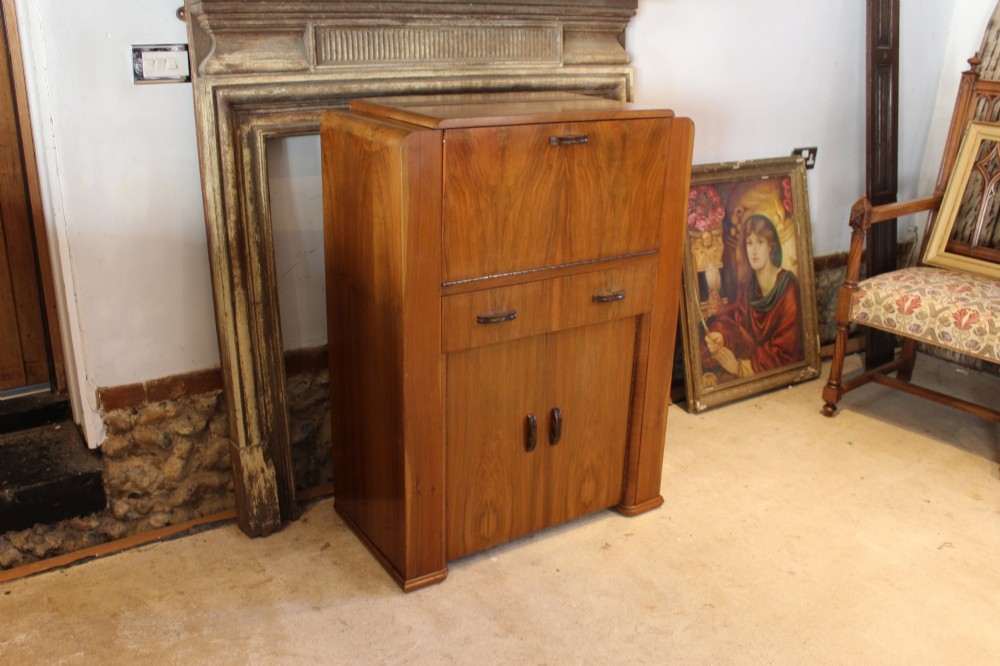 An Art Deco walnut bureau featuring a fall-front writing compartment above a single drawer and a two-door cupboard. View X