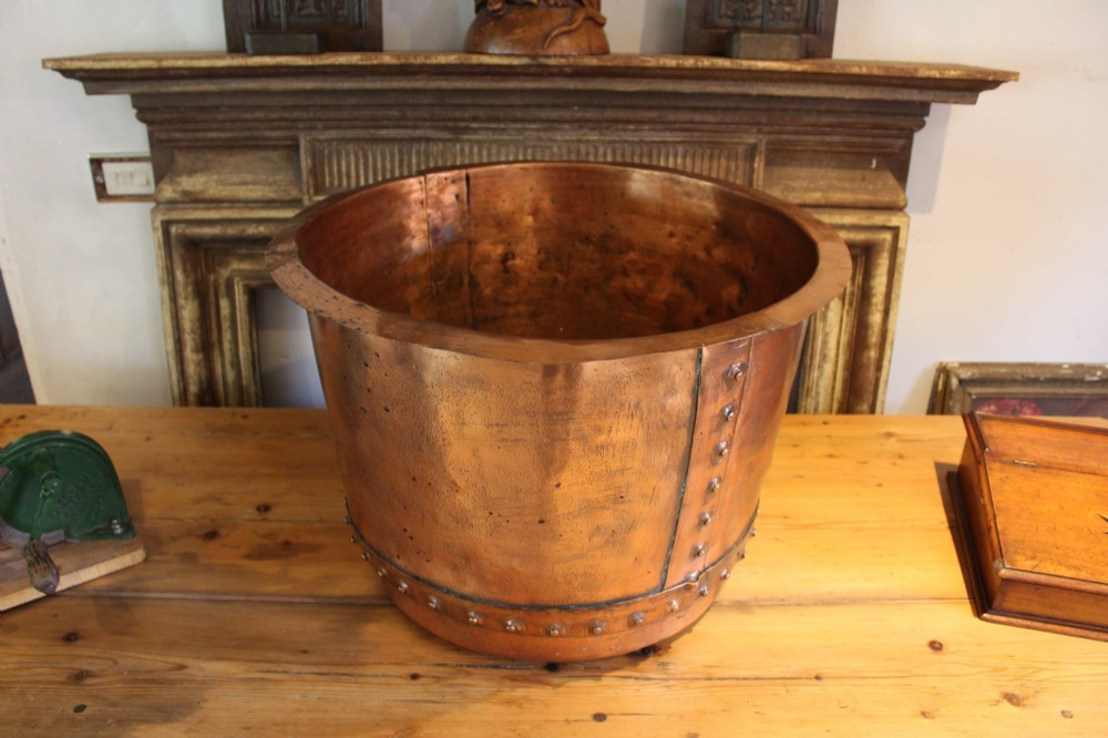 A large nineteenth-century Victorian copper vessel featuring a flared rolled rim and a hand-riveted vertical seam.