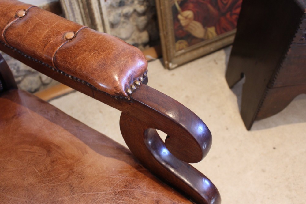 A William IV leather reclining armchair with carved mahogany frame, scrolled arms, brass stud trim, turned front legs, and castors. View V